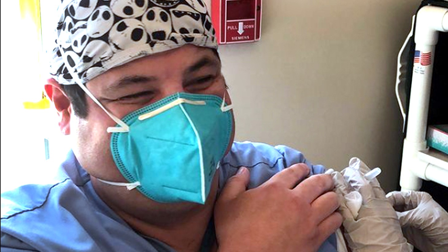 Young Latino man, wearing a blue mask, getting a vaccine 