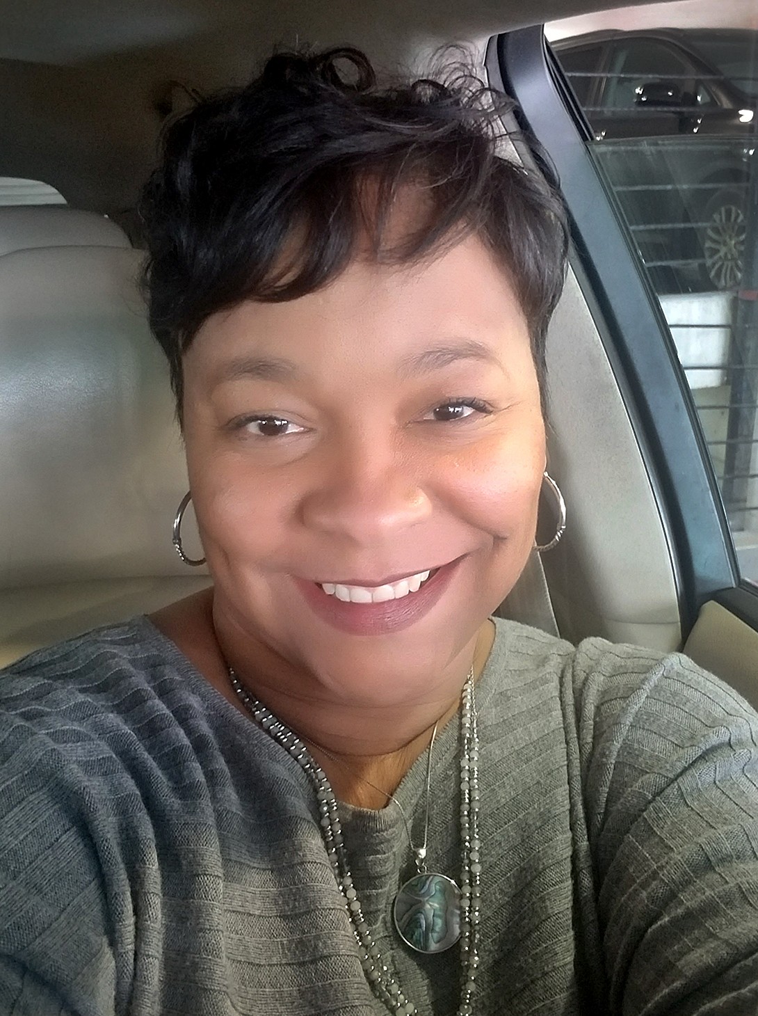 African American woman with a big smile sitting in a car.