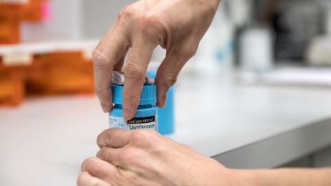 A pair of hands opening a blue medication bottle 