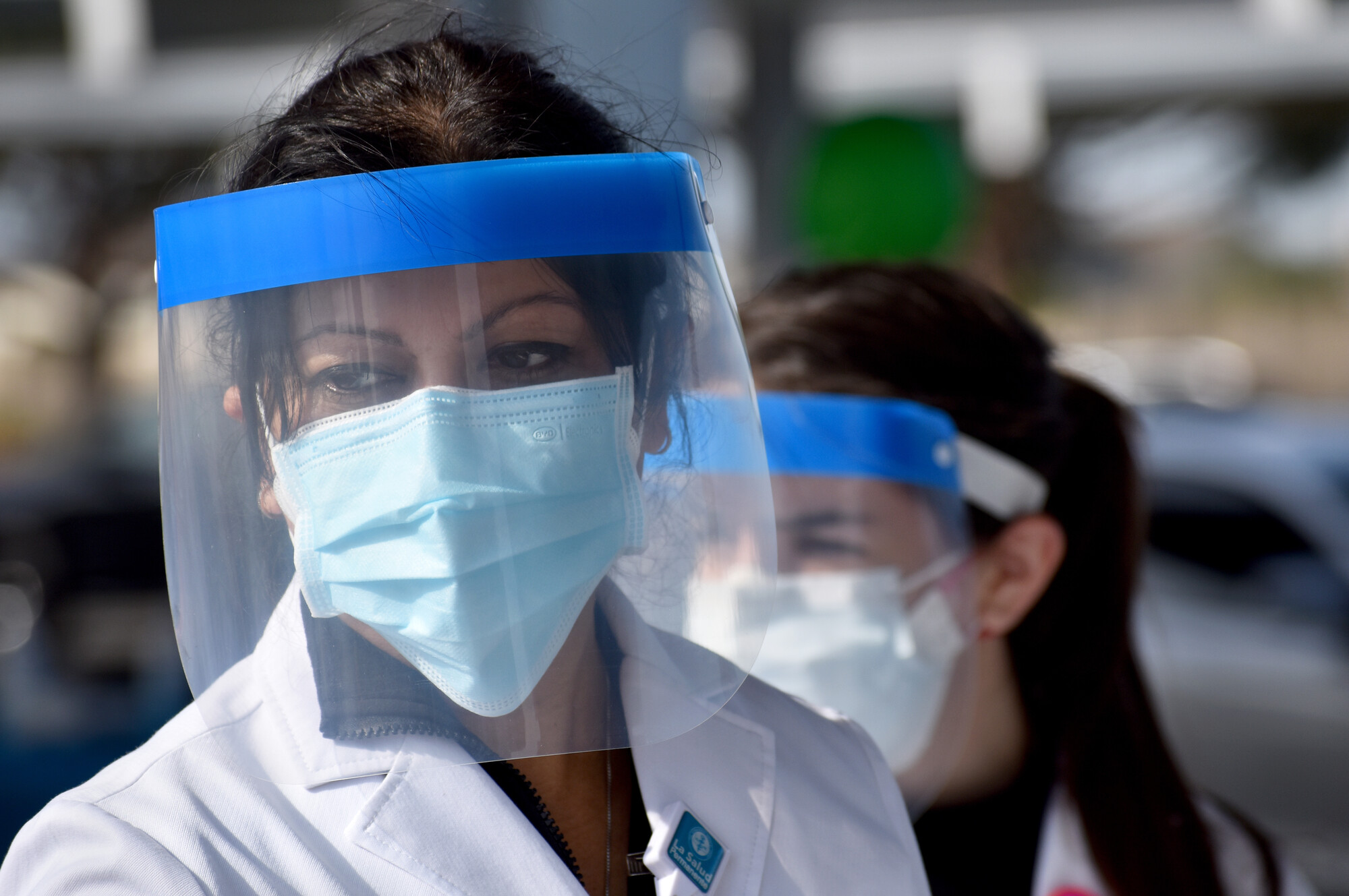 Two women in face shields and masks working at the drive-up hypertension clinic