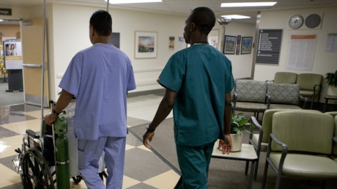 two transporters escorting a patient in a wheelchair