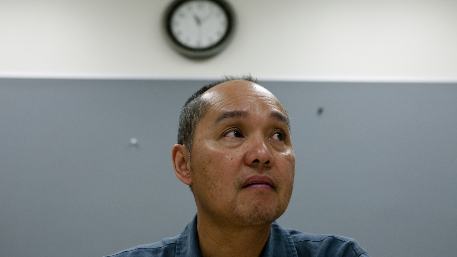 Anxious-looking man sitting under a clock 