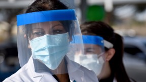 Two women in face shields and masks working at the drive-up hypertension clinic