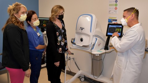 doctor in white lab coat showing three women a piece of medical equipment